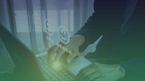 Image of hands at a laptop screen with customer experience sentiment emojis floating above.